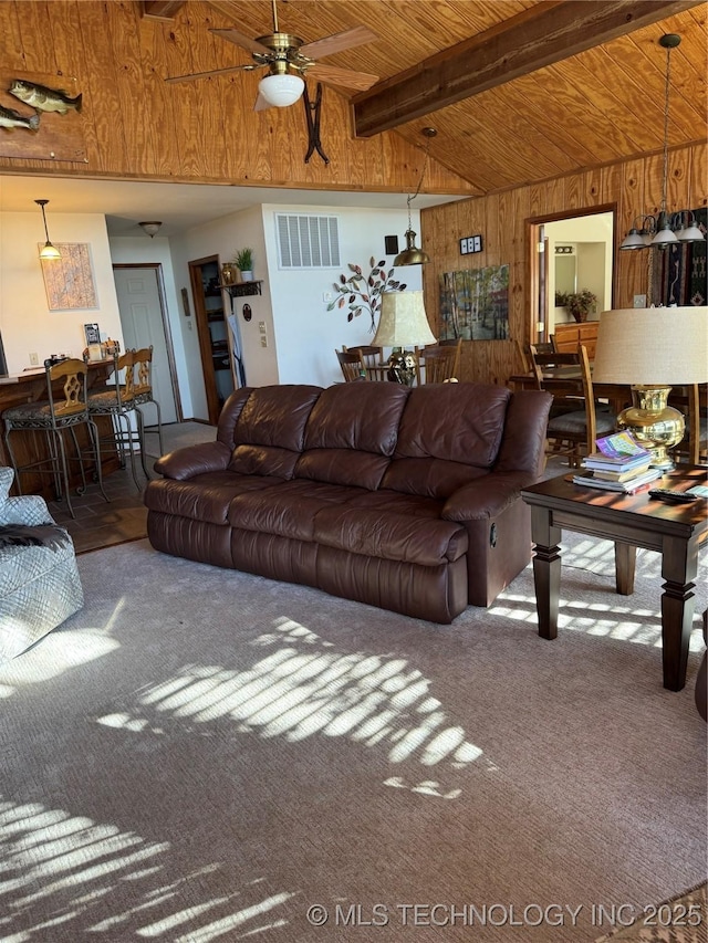 living room with carpet floors, visible vents, lofted ceiling with beams, wooden walls, and wooden ceiling