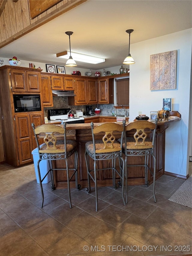 kitchen with backsplash, electric range oven, brown cabinetry, black microwave, and under cabinet range hood