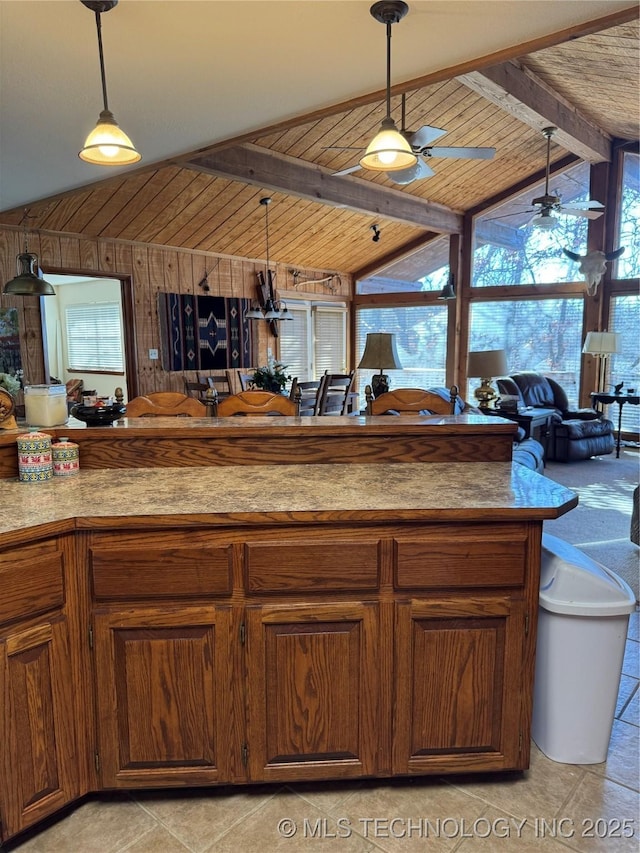 kitchen with lofted ceiling with beams, wooden walls, decorative light fixtures, and a ceiling fan