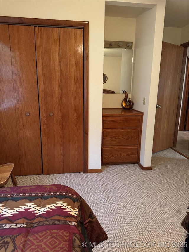 carpeted bedroom with a closet and baseboards