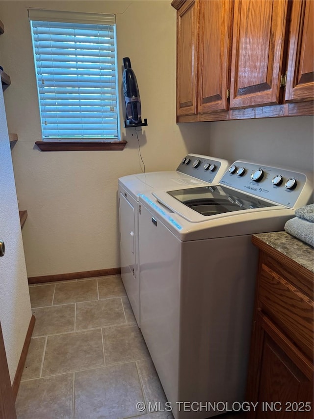 clothes washing area featuring baseboards, cabinet space, and washer and dryer