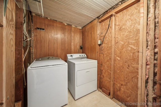 clothes washing area with laundry area, wood walls, and separate washer and dryer