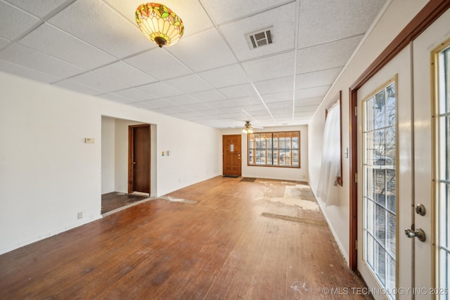 empty room featuring visible vents, ceiling fan, hardwood / wood-style floors, and a paneled ceiling