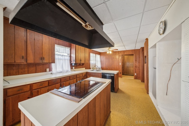 kitchen featuring brown cabinets, light countertops, a sink, a peninsula, and black appliances