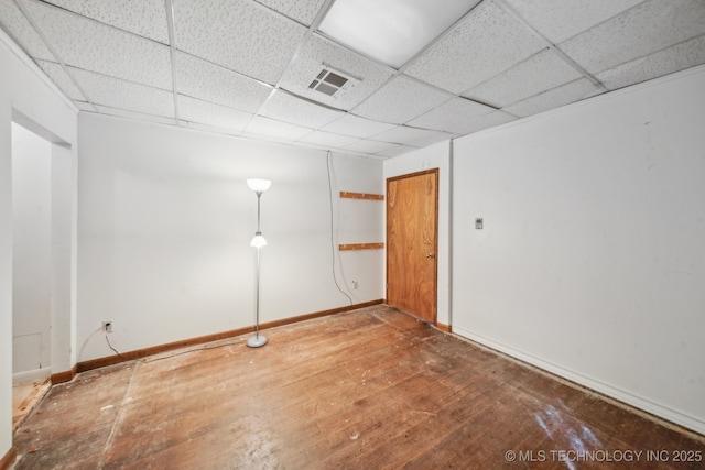 spare room with wood-type flooring, a drop ceiling, visible vents, and baseboards