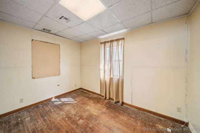 spare room featuring baseboards, visible vents, hardwood / wood-style floors, and a drop ceiling