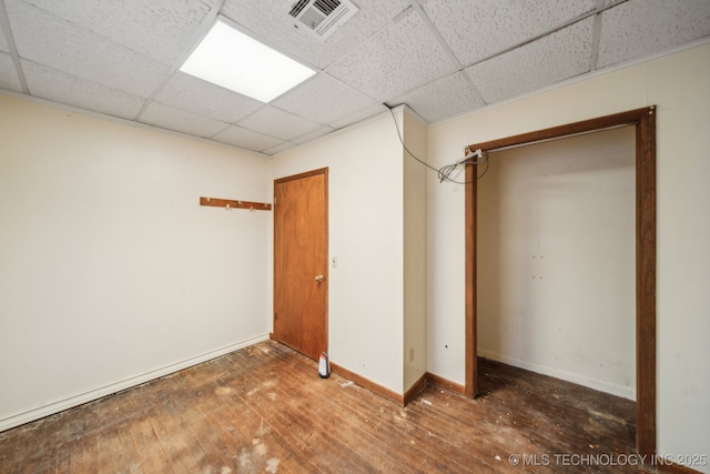 unfurnished bedroom featuring a paneled ceiling, visible vents, baseboards, and hardwood / wood-style flooring