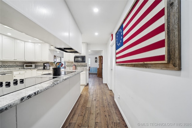 kitchen with black appliances, dark wood-style flooring, white cabinets, and decorative backsplash