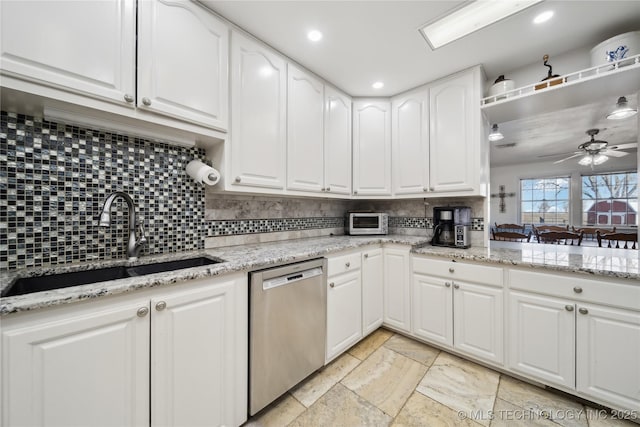 kitchen featuring a sink, a ceiling fan, white cabinetry, light stone countertops, and dishwasher