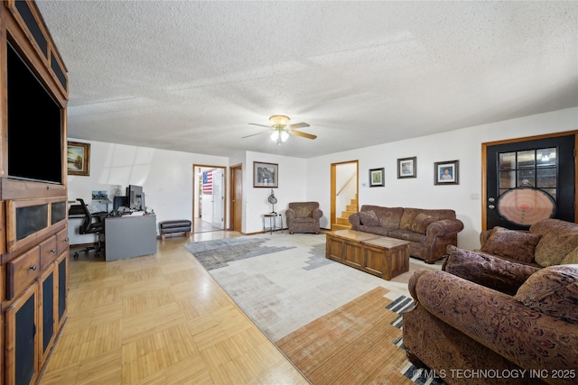 living room featuring a textured ceiling, a ceiling fan, and stairway