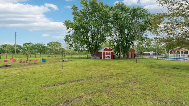 view of yard featuring fence, an outdoor structure, a barn, and a fenced in pool