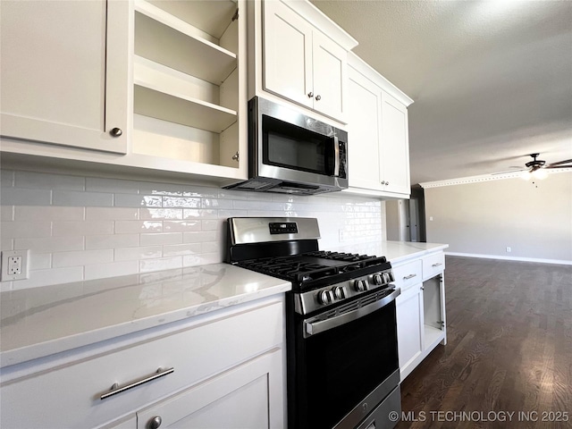 kitchen with decorative backsplash, appliances with stainless steel finishes, dark wood-style floors, white cabinetry, and a ceiling fan