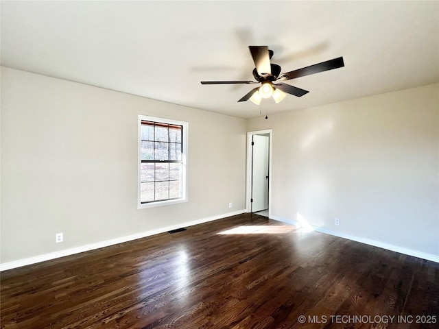 empty room with dark wood-type flooring, baseboards, visible vents, and ceiling fan