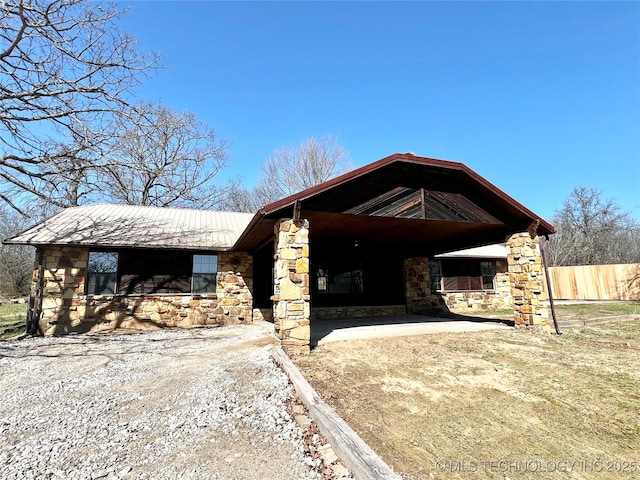 exterior space with fence, stone siding, and driveway