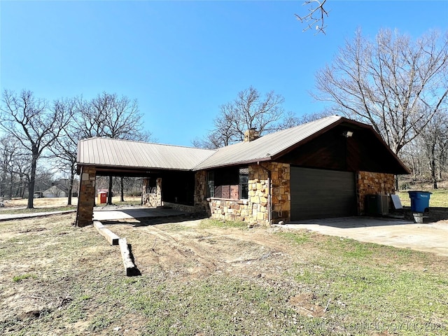 view of front of home featuring stone siding, driveway, metal roof, and a garage