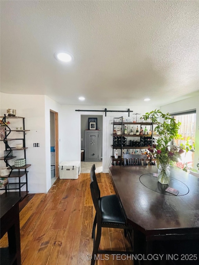 dining area featuring recessed lighting, wood finished floors, a textured ceiling, and a barn door