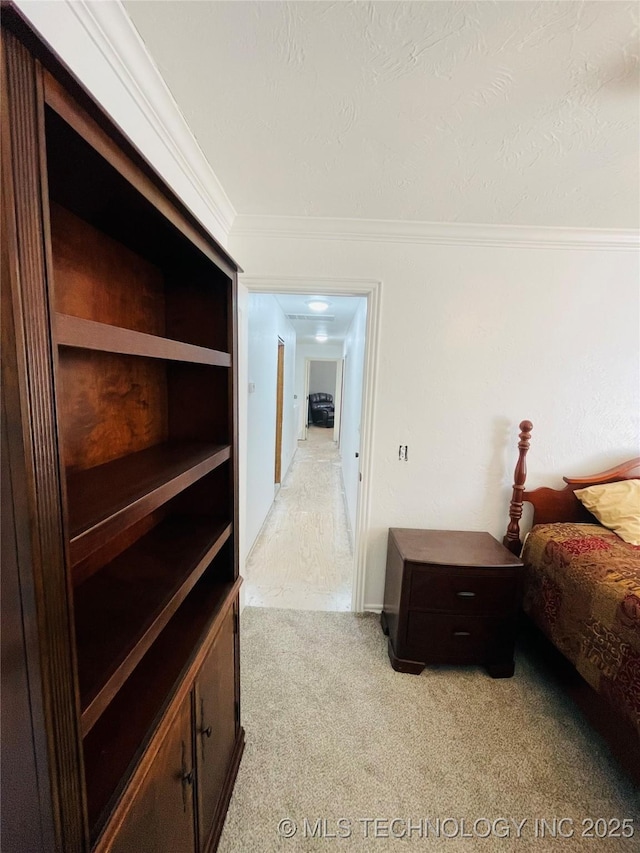 bedroom featuring light carpet, a textured ceiling, and crown molding