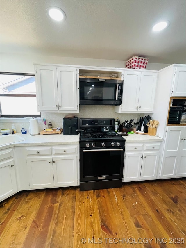 kitchen with black appliances, a sink, light countertops, and white cabinets