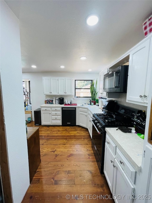 kitchen with black appliances, dark wood-type flooring, and white cabinetry