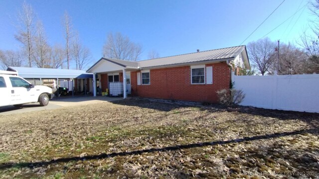 ranch-style home featuring metal roof, brick siding, and fence