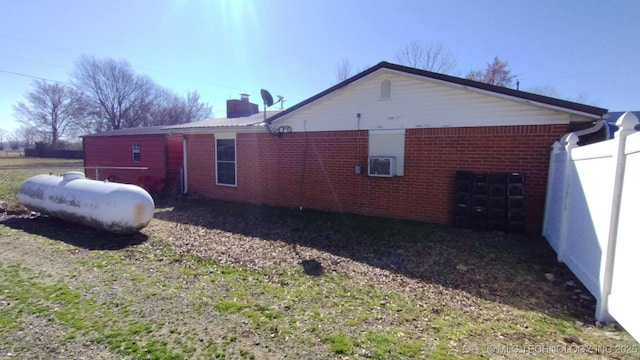 view of home's exterior featuring brick siding, cooling unit, and fence