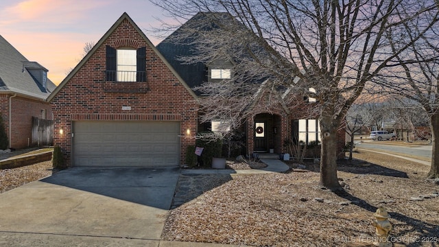 tudor house featuring a garage, concrete driveway, and brick siding