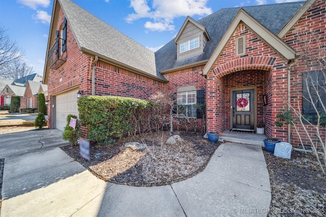 view of front facade featuring a garage, brick siding, driveway, and roof with shingles