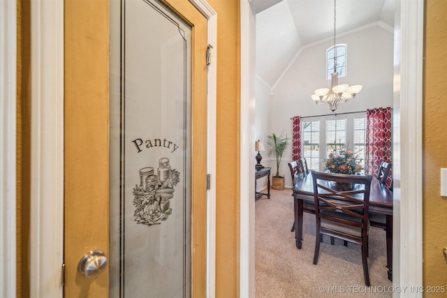 interior space featuring carpet floors, a chandelier, vaulted ceiling, and ornamental molding