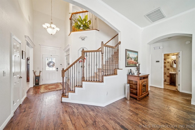 entryway featuring stairs, arched walkways, visible vents, and wood finished floors