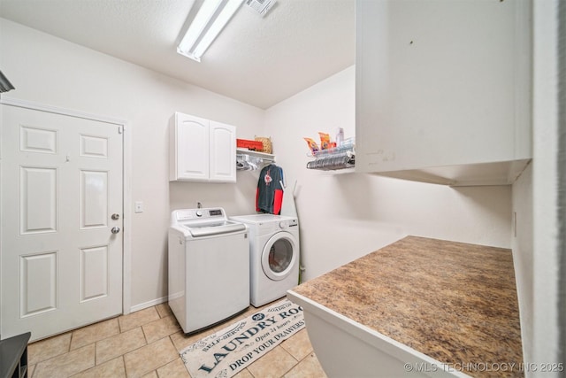 clothes washing area with visible vents, light tile patterned floors, washing machine and dryer, and cabinet space