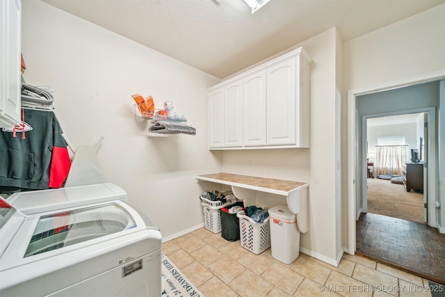 laundry area featuring light tile patterned flooring, independent washer and dryer, cabinet space, and baseboards