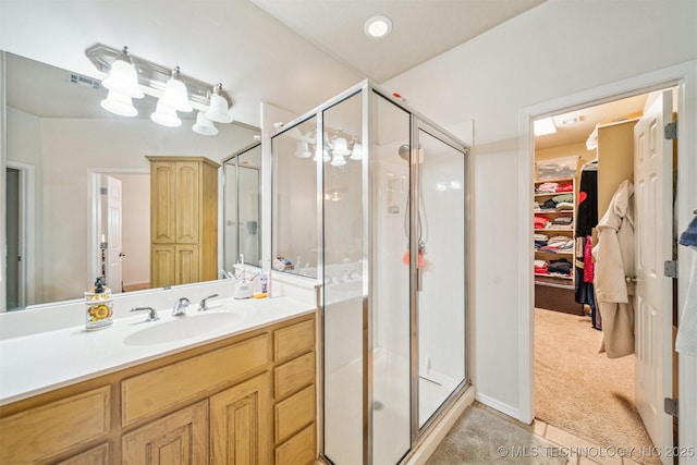 full bath with a spacious closet, a stall shower, vanity, and visible vents