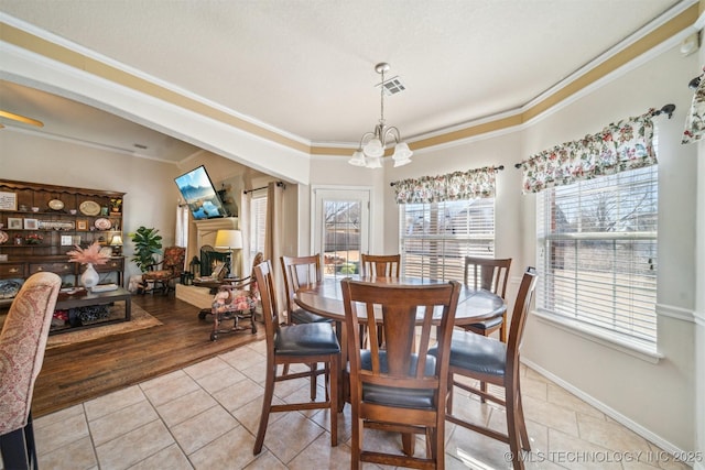 dining room with a notable chandelier, light tile patterned floors, visible vents, ornamental molding, and baseboards