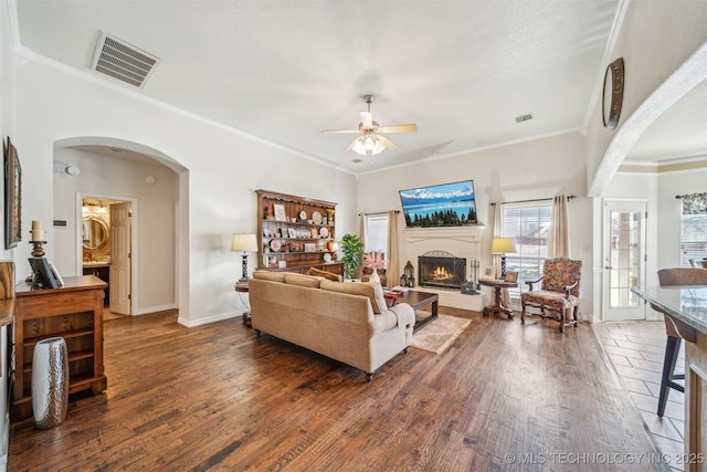 living room featuring a brick fireplace, visible vents, and wood finished floors