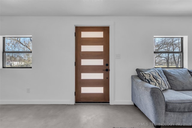 entryway with a healthy amount of sunlight, finished concrete floors, and baseboards