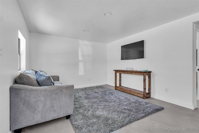 living area with concrete flooring and baseboards