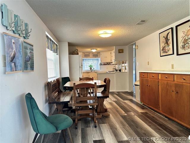 dining space with dark wood-style floors, visible vents, and a textured ceiling