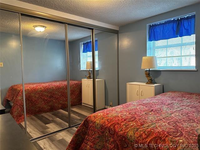 bedroom with a textured ceiling and wood finished floors