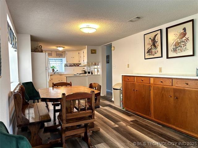 dining space with visible vents, dark wood finished floors, and a textured ceiling