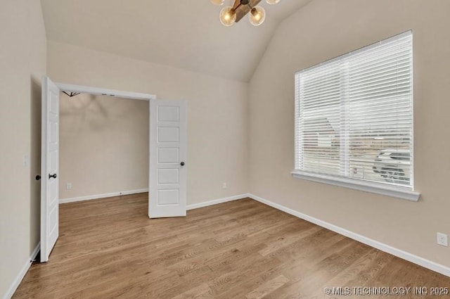 unfurnished bedroom with lofted ceiling, a notable chandelier, baseboards, and wood finished floors