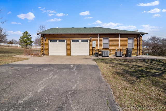 view of front of home with central AC unit, an attached garage, driveway, log siding, and a front lawn