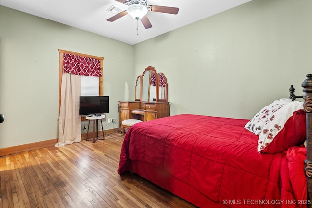 bedroom with hardwood / wood-style flooring, ceiling fan, visible vents, and baseboards