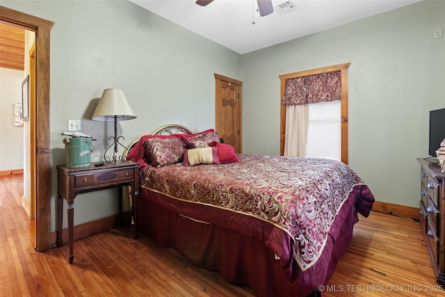 bedroom with a ceiling fan, hardwood / wood-style flooring, visible vents, and baseboards