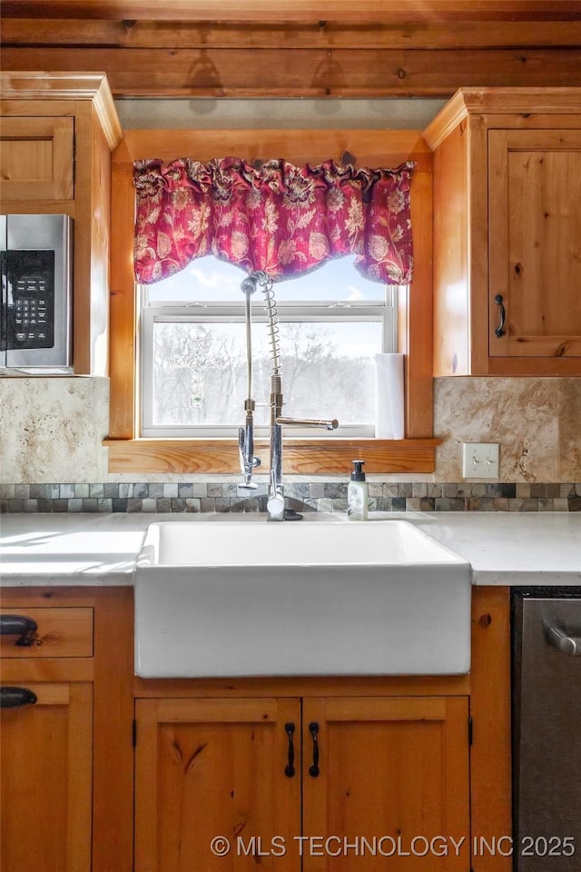 kitchen featuring appliances with stainless steel finishes, plenty of natural light, a sink, and backsplash