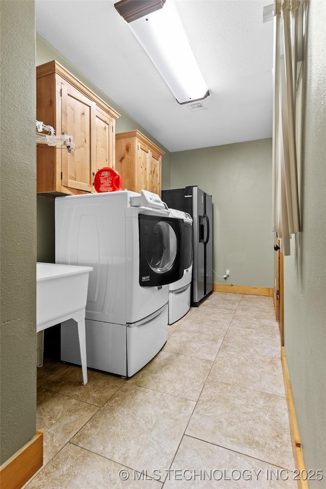 clothes washing area with cabinet space, washer and clothes dryer, and baseboards