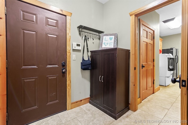 interior space featuring light tile patterned flooring, washer / dryer, and baseboards