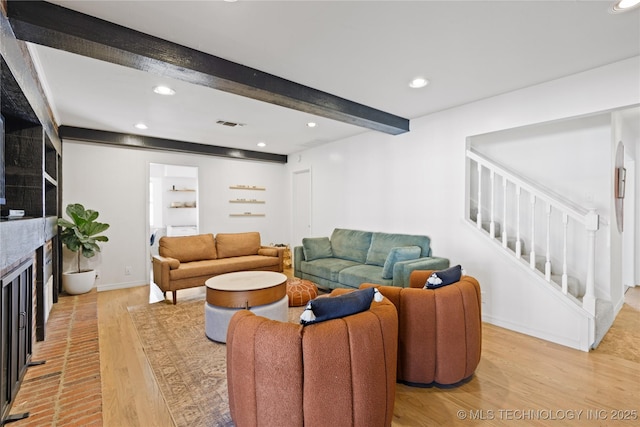 living room with light wood-style flooring, recessed lighting, beamed ceiling, and stairway