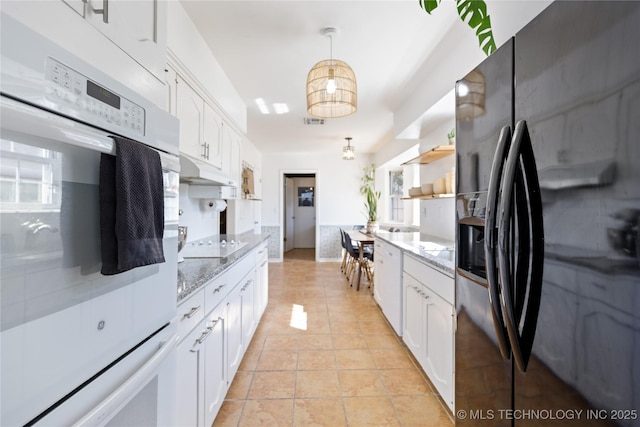 kitchen with light tile patterned floors, electric stovetop, visible vents, white cabinets, and black fridge