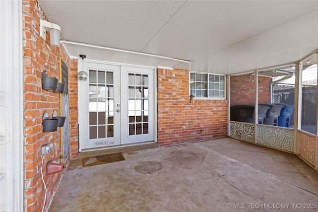 view of exterior entry with a patio, french doors, and brick siding