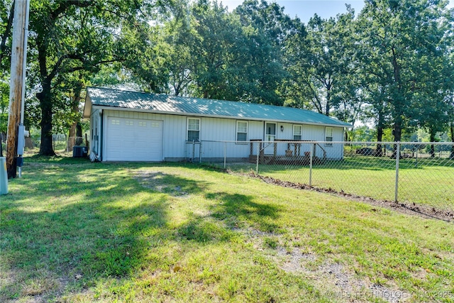 view of front of property with an attached garage, metal roof, fence private yard, driveway, and a front lawn